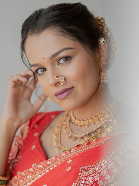 Close-up makeup portrait with a coral sari, warm lip colour and gold jewellery, from Pooja Salunkhe Makeover's portfolio